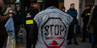 Ein Mann steht mit dem Rücken zur Kamera, auf seiner Jeansjacke steht "Stop Zwangsräumungen"