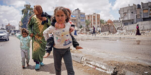 Ein Mädchen trägt ihre kleine Schwester auf dem Rücken und flieht mit ihrer Familie vor der Israelischen Offensive aus Rafah