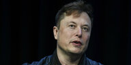 Elon Musk vor dunklem Hintergrund
