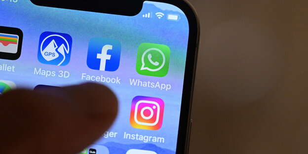 Eine Hand hält ein iPhone, auf dem Sozial Media Apps dargestellt sind.