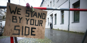 Pappschild mit der Aufschrift "We stand by your side", im Hintergrund ein Polizist