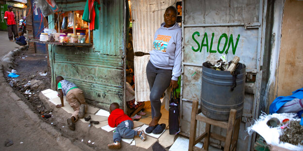 Ein Frau mit ihren Kindern vor ihrem Salon im Kibera-Slum in Nairobi