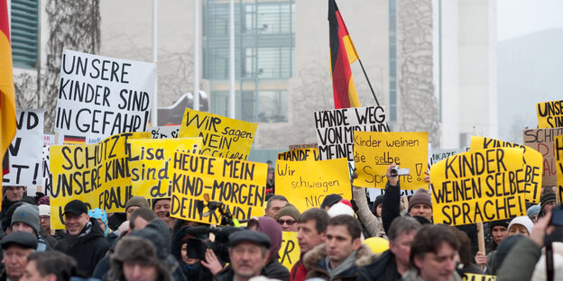 Rassistisch aufgehetzte Demonstrant_innen tragen Deutschlandfahnen und Schilder „Unsere Kinder sind in Gefahr“ Rassistisch aufgehetzte Demonstrant_innen tragen Deutschlandfahnen und Schilder „Unsere Kinder sind in Gefahr“