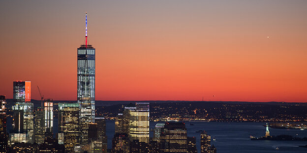 Hinter der Skyline Manhattans mit erleuchteten Fenster zeigt sich ein rosiger Sonnenuntergang. Hinter der Skyline Manhattans mit erleuchteten Fenster zeigt sich ein rosiger Sonnenuntergang.