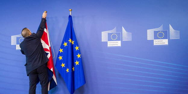 EU-Mitarbeiter richtet Großbritannien- und Europa-Flagge EU-Mitarbeiter richtet Großbritannien- und Europa-Flagge