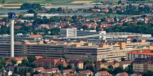 das Quelle-Gebäude, im Vordergrund kleinere Häuser, im Hintergrund Felder