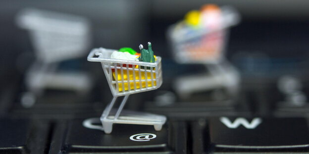 Ein Miniatur-Einkaufswagen steht auf einer Computertastatur Ein Miniatur-Einkaufswagen steht auf einer Computertastatur