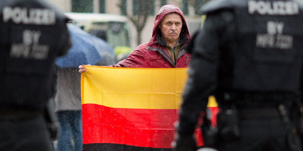 Ein Teilnehmer einer Kundgebung der Bürgerinitiative "Sichere Heimat" hält eine umgedrehte Deutschland-Flagge in den Händen Ein Teilnehmer einer Kundgebung der Bürgerinitiative "Sichere Heimat" hält eine umgedrehte Deutschland-Flagge in den Händen