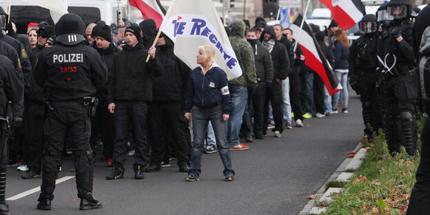 Ein Gruppe rechter Demonstranten trifft auf einer Straße auf Polizisten.