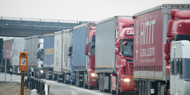 Mehrere Lastwagen stehen hintereinander auf einer Straße Mehrere Lastwagen stehen hintereinander auf einer Straße