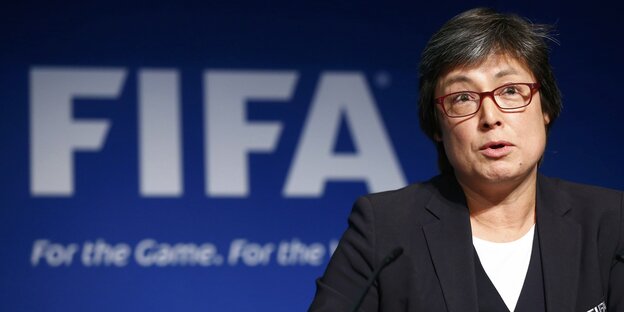 Eine Frau mit Brille im Anzug. Sitzt vor einer Wand mit dem Schriftzug Fifa. Eine Frau mit Brille im Anzug. Sitzt vor einer Wand mit dem Schriftzug Fifa.