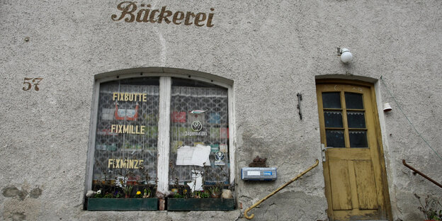 Im Fenster einer Bäckere wird für „Fixbutte, Fixmille, Fixminze“ geworben, daneben eine alte braune Eingangstür. Im Fenster einer Bäckere wird für „Fixbutte, Fixmille, Fixminze“ geworben, daneben eine alte braune Eingangstür.