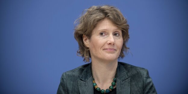 Eine Frau schaut freundlich in die Kamera, sie trägt ein Jackett und eine Kette. Eine Frau schaut freundlich in die Kamera, sie trägt ein Jackett und eine Kette.