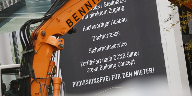 Bagger vor einem Bauschild Bagger vor einem Bauschild