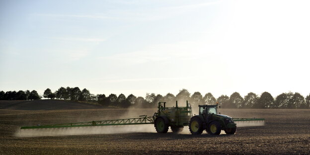 Ein Traktor spritzt Pestizid auf einen Acker