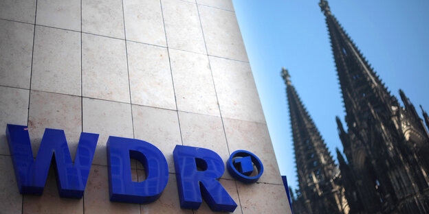 Der Schriftzug WDR an einem Haus, daneben die Türme des Kölner Doms Der Schriftzug WDR an einem Haus, daneben die Türme des Kölner Doms