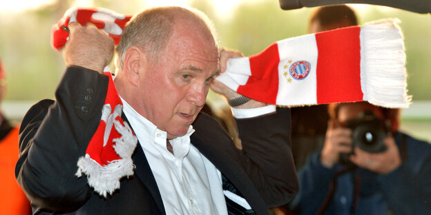 Uli Hoeneß legt sich einen Schal des FC Bayern um. Uli Hoeneß legt sich einen Schal des FC Bayern um.