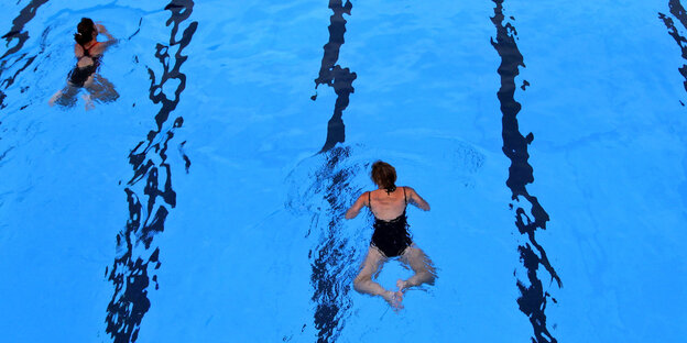 Zwei Frauen ziehen ihre Bahnen im Schwimmbad. Sie halten Abstand Zwei Frauen ziehen ihre Bahnen im Schwimmbad. Sie halten Abstand