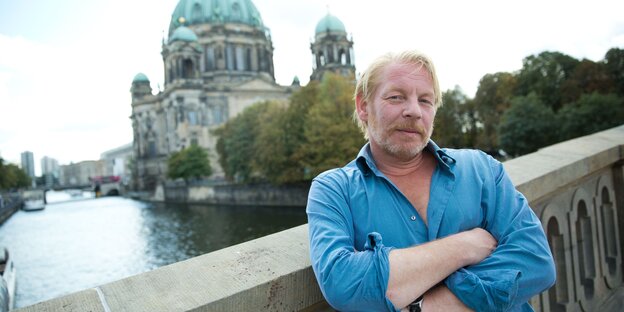 Blonder Mann steht auf Brücke in Berlin. Im Hintergrund ist die Spree zu sehen. Blonder Mann steht auf Brücke in Berlin. Im Hintergrund ist die Spree zu sehen.