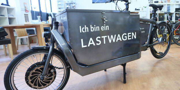 Ein grausilbernes Lastenfahrrad mit einer großen Transportkiste und der Aufschrift "ich bin ein Lastwagen"