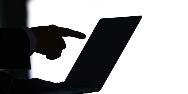Eine Hand zeigt auf einen Laptop. Eine Hand zeigt auf einen Laptop.