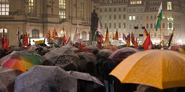 Pegida-Anhänger in Dresden mit Schirmen und Deutschlandfahnen Pegida-Anhänger in Dresden mit Schirmen und Deutschlandfahnen