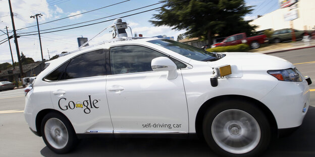 Ein weißes Auto mit der Aufschrift "Google" auf einer Straße Ein weißes Auto mit der Aufschrift "Google" auf einer Straße