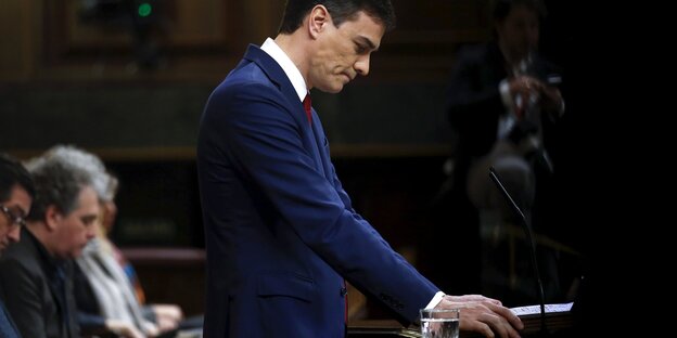Pedro Sánchez steht an einem Rednerpult und schaut zu Boden Pedro Sánchez steht an einem Rednerpult und schaut zu Boden