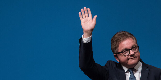 Mann in Anzug mit Brille winkt Mann in Anzug mit Brille winkt