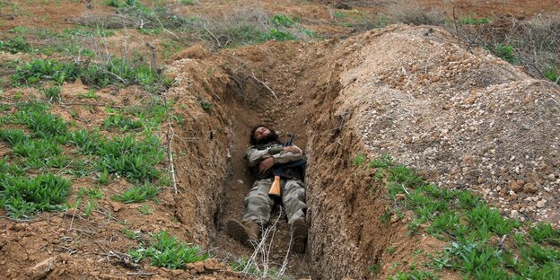 Ein syrischer Kämpfer schalft mit seinem Gefahr in einem Erdloch. Ein syrischer Kämpfer schalft mit seinem Gefahr in einem Erdloch.