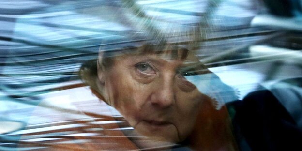 Frau Merkel blickt hinter einer reflektierenden Autofensterscheibe hervor. Frau Merkel blickt hinter einer reflektierenden Autofensterscheibe hervor.