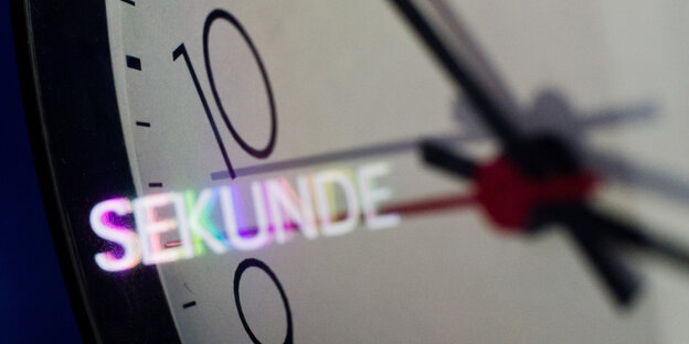 Das Ziffernblatt einer Uhr, es spiegelt sich das Wort Sekunde darin. Das Ziffernblatt einer Uhr, es spiegelt sich das Wort Sekunde darin.