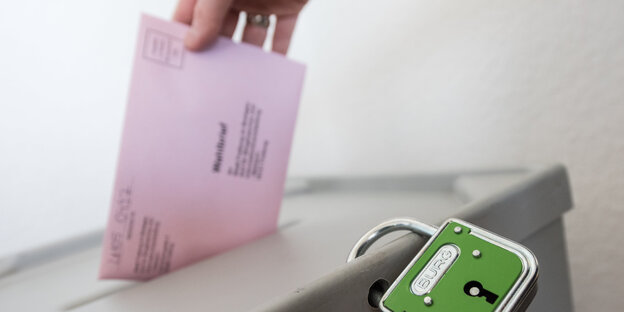 Ein Wahlzettel wird in eine Urne gesteckt Ein Wahlzettel wird in eine Urne gesteckt