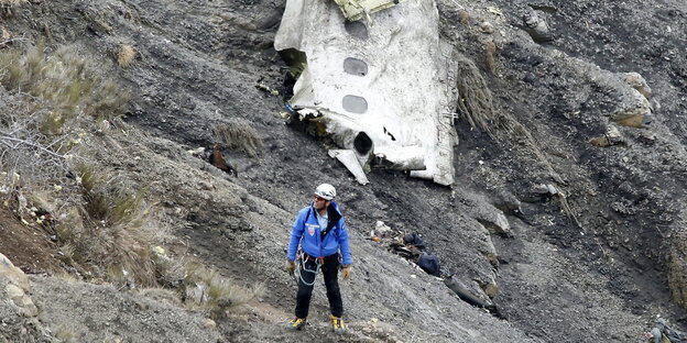 Ein Mann mit Kletterausrüstung vor einem Flugzeugteil Ein Mann mit Kletterausrüstung vor einem Flugzeugteil