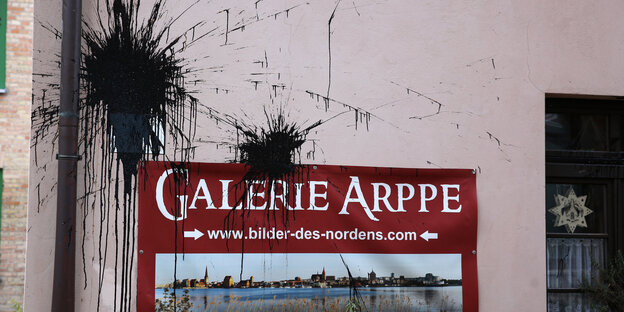 Schwarze Farbkleckse auf einer rosafarbenen Hauswand und einem Schild „Galerie Arppe“. Schwarze Farbkleckse auf einer rosafarbenen Hauswand und einem Schild „Galerie Arppe“.