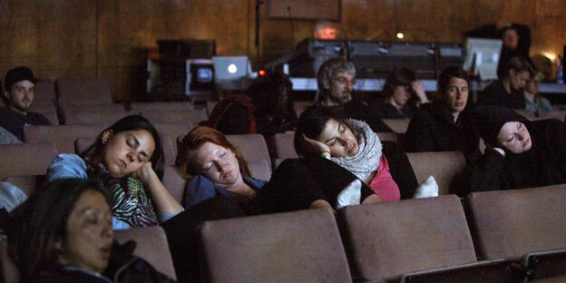 Menschen sitzen schlafend in einem Theaterraum. Menschen sitzen schlafend in einem Theaterraum.