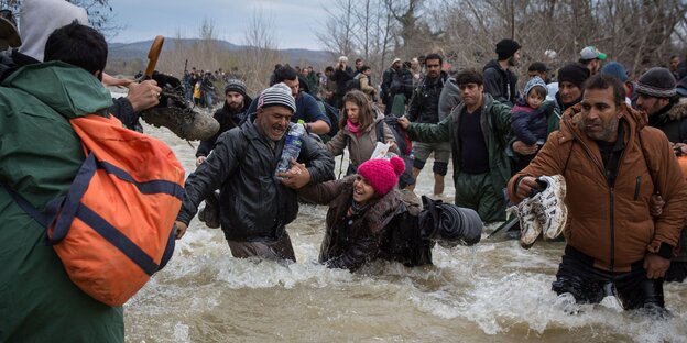 Menschen stehen in einem Fluss mit reißendem Wasser Menschen stehen in einem Fluss mit reißendem Wasser