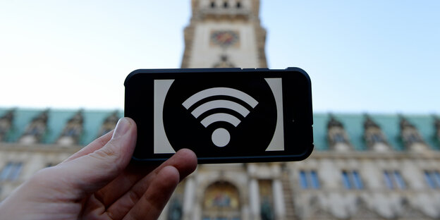 EIn Mann hat ein Handy mit einem WLAN Symbol in der Hand EIn Mann hat ein Handy mit einem WLAN Symbol in der Hand