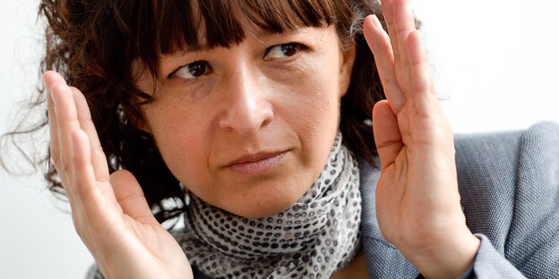 Emmanuelle Charpentier hält die Hände rechts und links neben den Kopf Emmanuelle Charpentier hält die Hände rechts und links neben den Kopf