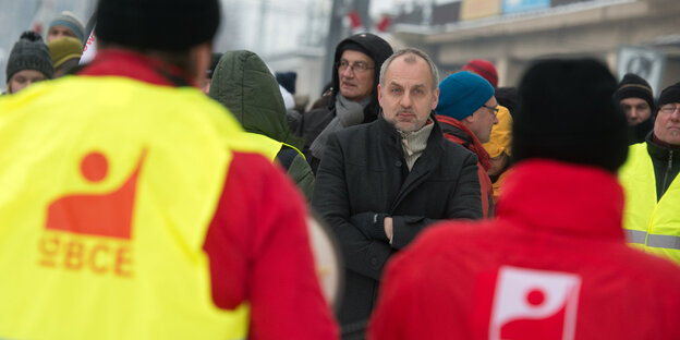 Ein Mann, umgeben von Männern mit Streikwesten Ein Mann, umgeben von Männern mit Streikwesten