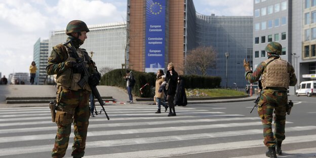 Soldaten mit Helm und Gewehren stehen auf der Straße vor einem Gebäude Soldaten mit Helm und Gewehren stehen auf der Straße vor einem Gebäude