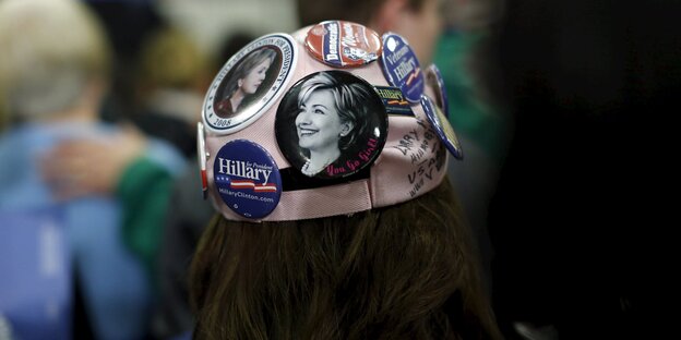 Eine Mütze mit Buttons, die das Gesicht von Hillary Clinton zeigen Eine Mütze mit Buttons, die das Gesicht von Hillary Clinton zeigen