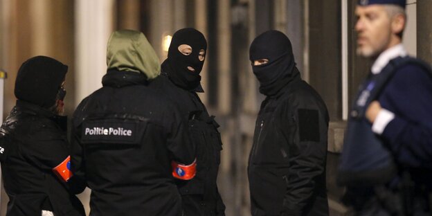 maskierte Polizisten sprechen miteinander, es ist dunkel maskierte Polizisten sprechen miteinander, es ist dunkel