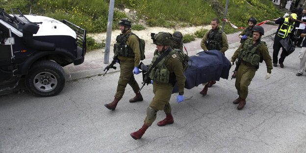 Mehrere Soldaten tragen eine Bahre mit einem von einer Decke bedeckten Toten Mehrere Soldaten tragen eine Bahre mit einem von einer Decke bedeckten Toten
