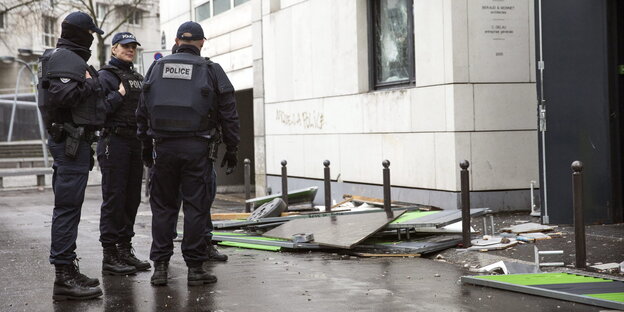 Drei Polizisten stehen auf der Straße. Neben ihnen Gerümpel Drei Polizisten stehen auf der Straße. Neben ihnen Gerümpel
