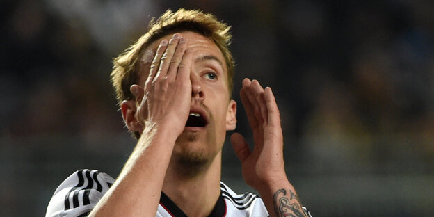Der Fußballer Max Kruse hält sich die Hand vor das Gesicht Der Fußballer Max Kruse hält sich die Hand vor das Gesicht