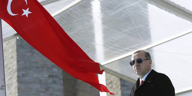 Recep Tayyip Erdogan steht mit Sonnenbrille neben der türkischen Flagge Recep Tayyip Erdogan steht mit Sonnenbrille neben der türkischen Flagge