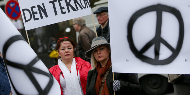 Menschen mit „Peace-Zeichen“- und „Stoppt den Terror“-Plakaten