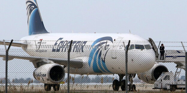 Ein Flugzeug steht hinter einem Zaun Ein Flugzeug steht hinter einem Zaun