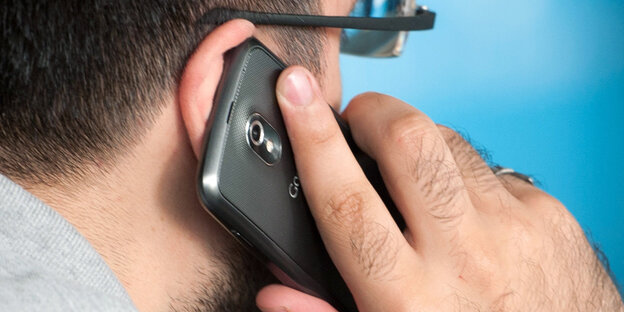 Ein Mann hält ein Smartphone an sein Ort. Ein Mann hält ein Smartphone an sein Ort.